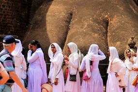 Queue of the women in beautiful, violet, pink and white clothing on Sigiriya, Sri Lanka