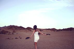 Back view of a woman in white clothes, posing on the beautiful landscape