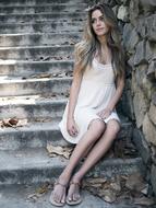 Beautiful Girl sits on stone steps at wall