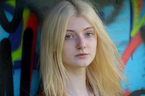 Portrait of the beautiful, young, blonde girl, near the wall with colorful graffities