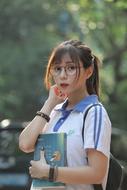 Asian girl with glasses and books, outdoors