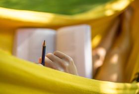 woman with a book lies in a hammock on a blurred background