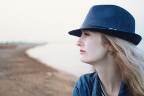blonde in a hat on the beach in a blurred background