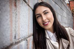 Portrait of the smiling woman, laying on the wall