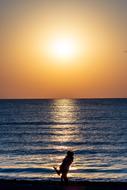 Silhouette of the people in love, on the beach, at beautiful and colorful sunrise in the sky