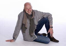 a man in a scarf sits on the ground