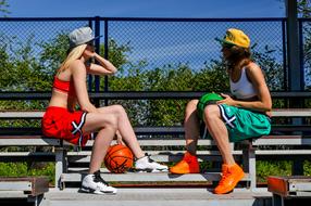 Woman in colorful clothing, with basketball ball, in sunlight, near the green trees