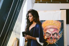 Profile portrait of the beautiful girl with cup of coffee, near the colorful graffiti on the wall