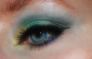 Close-up of the girl's eye with colorful, shiny make-up