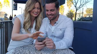 young couple with phone in a street cafe