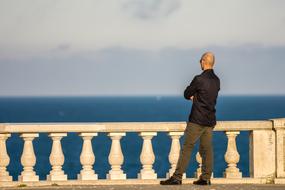 a man stands on a bridge near the sea