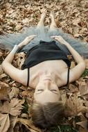 girl lies on autumn leaves in the forest