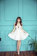 young asian woman in white posing near the wall
