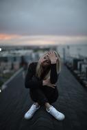 slim Girl in despair sit rooftop in city
