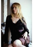 blonde in a guipure dress against a white wall
