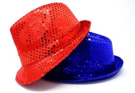 Close-up of the shiny, red and blue hats with the sequins, with the shadows, on white surface