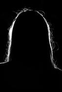 Dark silhouette of a woman, with backlight, at black background