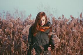 Young girl in jacket, among the colorful and beautiful plants on the field