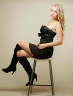 girl in a short black dress sits on a chair