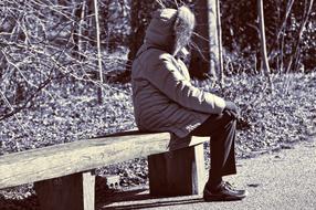 Black and white photo of the woman, sitting on the wooden bench, near the plants