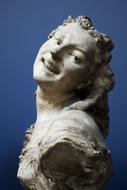 Sculpture of the smiling woman in light, at blue background
