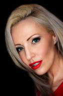 Portrait of the blonde Zara Watson with make-up and earrings, at black background