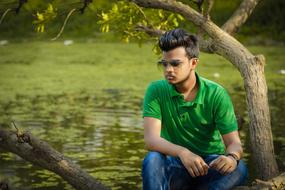 Bearded man with sunglasses, on the shore of the water, among the plants