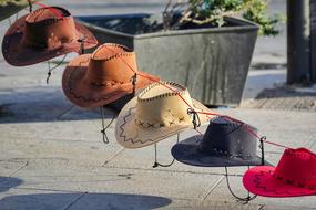 Colorful cowboy hats on the rope, above the pavement in sunlight
