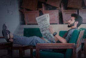 man with a newspaper in a chair indoors