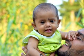 Portrait of the cute girl kid with the father, at blurred background with colorful plants