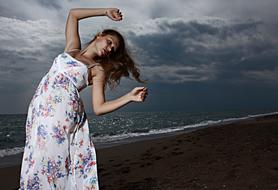 Woman in the colorful dress, on the dark landscape, under the clouds