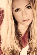 Portrait of the blonde woman in red clothing, in light