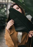 girl posing with a large green leaf