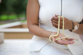 white rosary for prayer in hands close-up