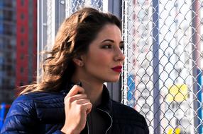 woman with wavy hair on the background of a metal lattice