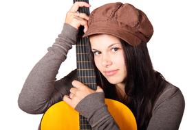Girl in brown cap posing with the acoustic guitar, at white background