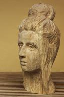 Wooden sculpture of the woman's head, on the wooden surface