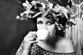 Black and white photo of the woman with the flowers with the leaves, drinking from the cup