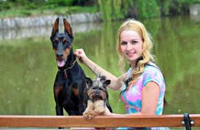 Blonde woman with colorful, beautiful and cute dogs, on the bench, near the water