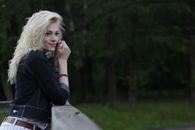 girl near the fence against the background of the forest during a photo shoot