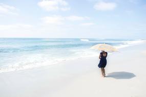 girl with an umbrella walking on the beach