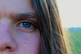 Close-up of the half of the face of the girl, with the hair, at colorful background