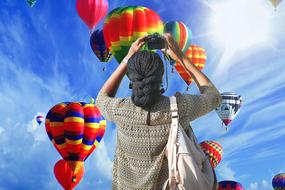 woman takes pictures of multicolored hot air balloons