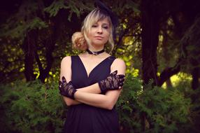 Portrait of the blonde woman in dark clothing, near the plants in the park