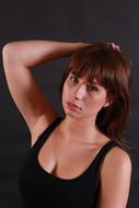 Portrait of the woman in black top, posing at grey background