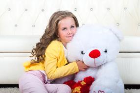 Smiling girl with curly hair, near the colorful, cute Teddy Bear