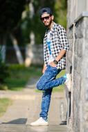 a guy in stylish clothes stands near the wall on a blurred background