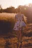 Girl in short dress walks away on path in countryside