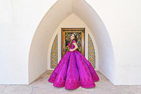 Beautiful, smiling girl in the colorful dress on QuinceaÃ±era, near the colorful architecture