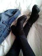 female legs in black boots on the bed